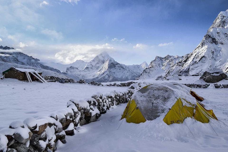 Zelt vor schneebedeckten Bergen beim Trekking